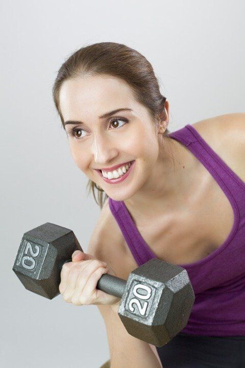 a girl with a dumbbell exercises to lose weight